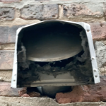 An exterior exhaust vent clogged with lint and debris before cleaning by The Dryer Vent Guy.