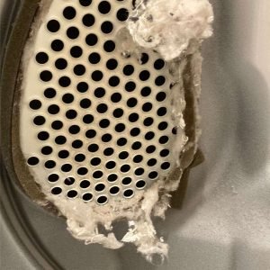 Dryer lint filter duct cover showing a damaged gasket before being replaced.